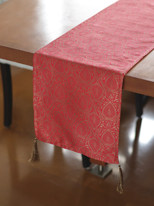 Red patterned table runner with tassels on a wooden table