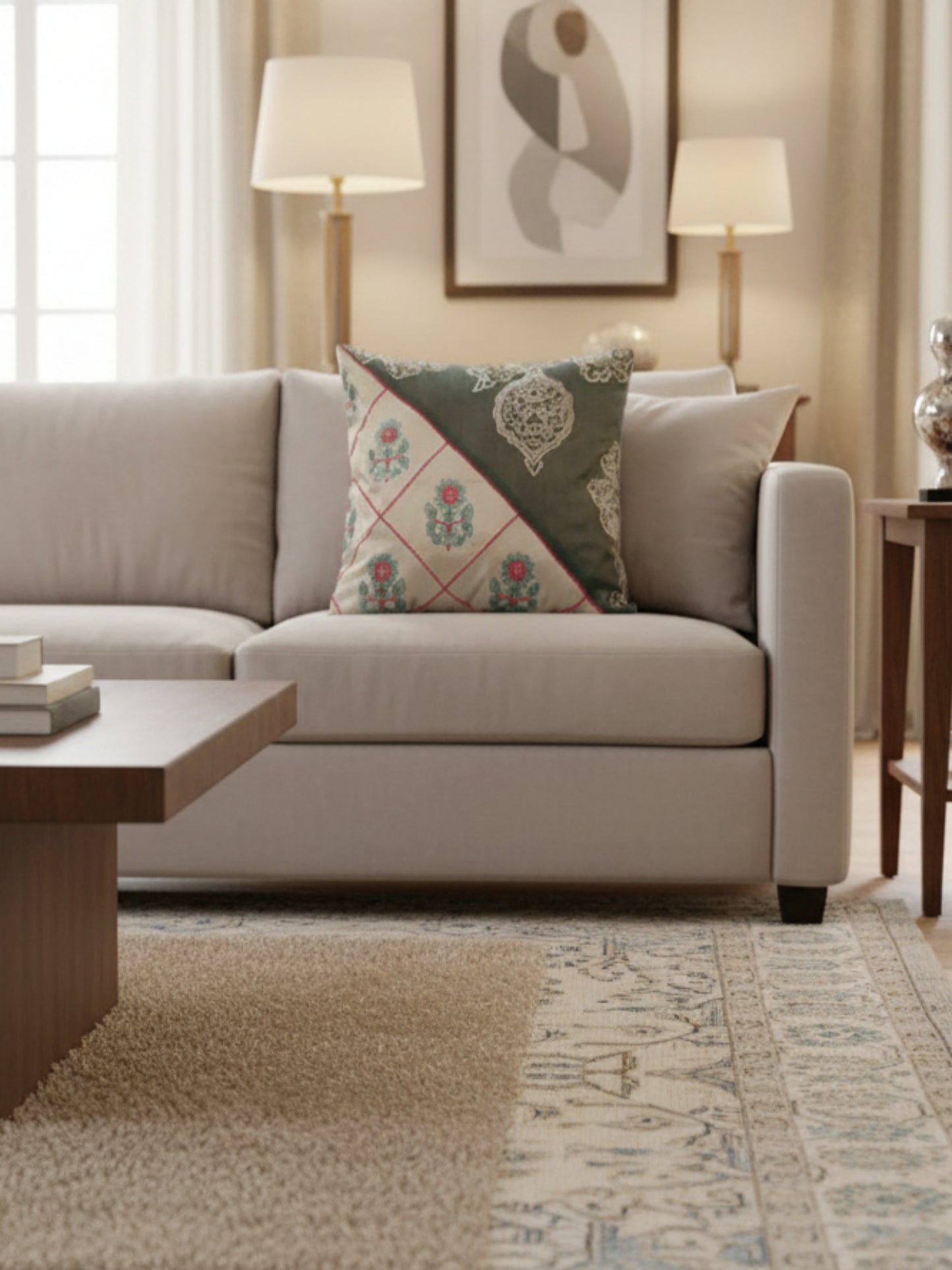 A square decorative throw pillow with a diagonal split design. One half is a dark gray-green fabric with beige traditional embroidery, and the other half is cream-colored with a pink diamond grid and teal floral motifs.