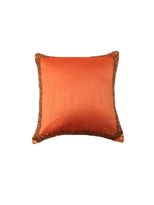 An orange square cushion cover with sequin work on the border.