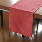 Red patterned table runner with tassels on a wooden table