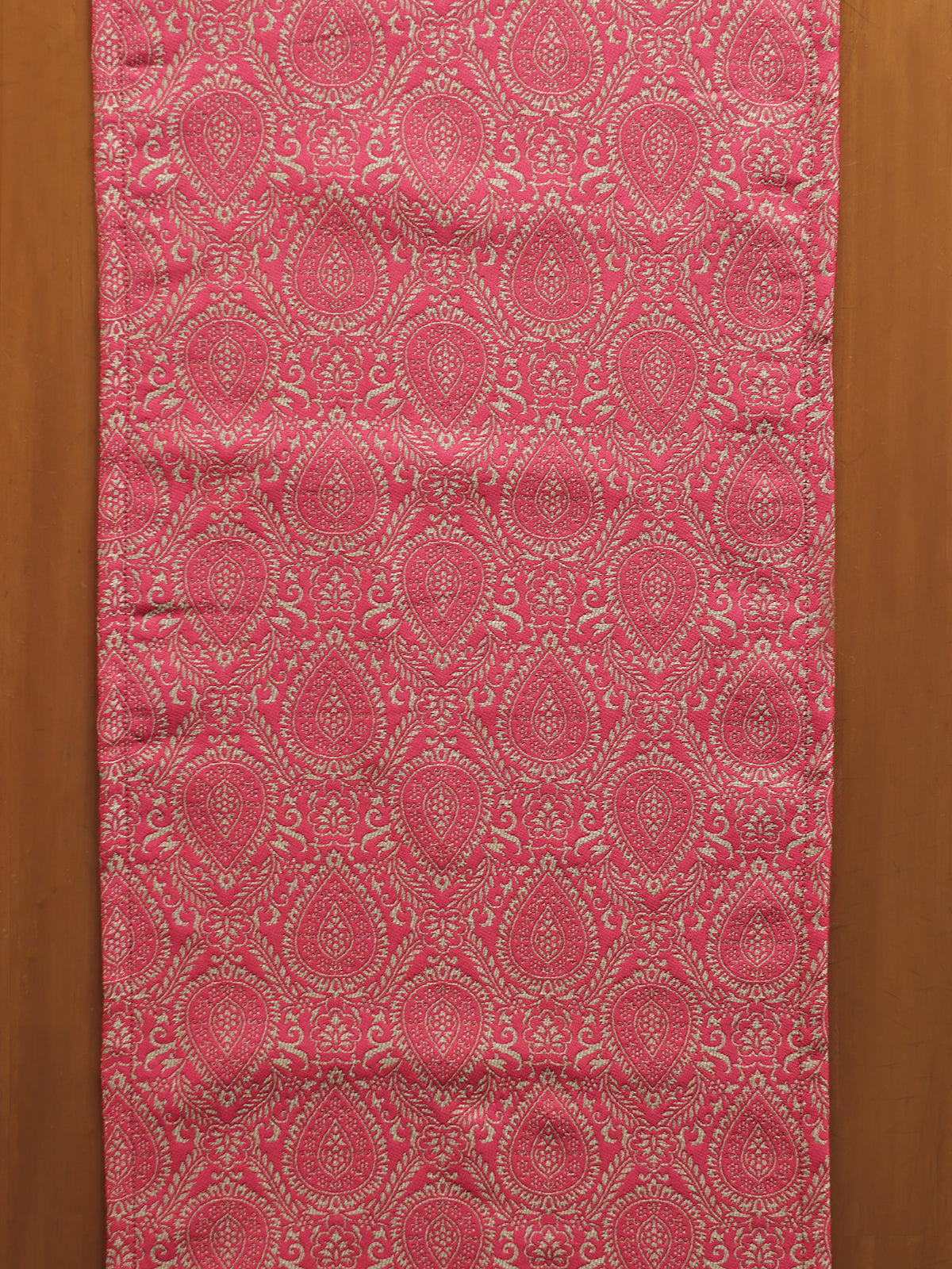 Red fabric with intricate pattern on a wooden background