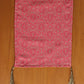 Pink patterned fabric with tassels on a wooden surface