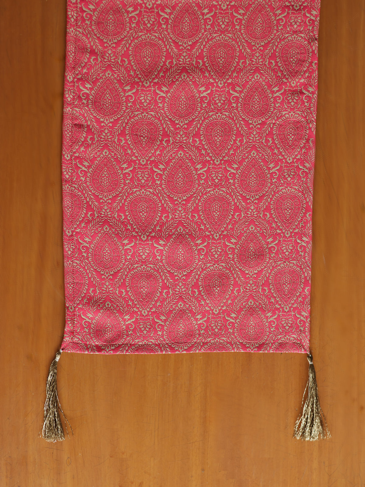 Pink patterned fabric with tassels on a wooden surface