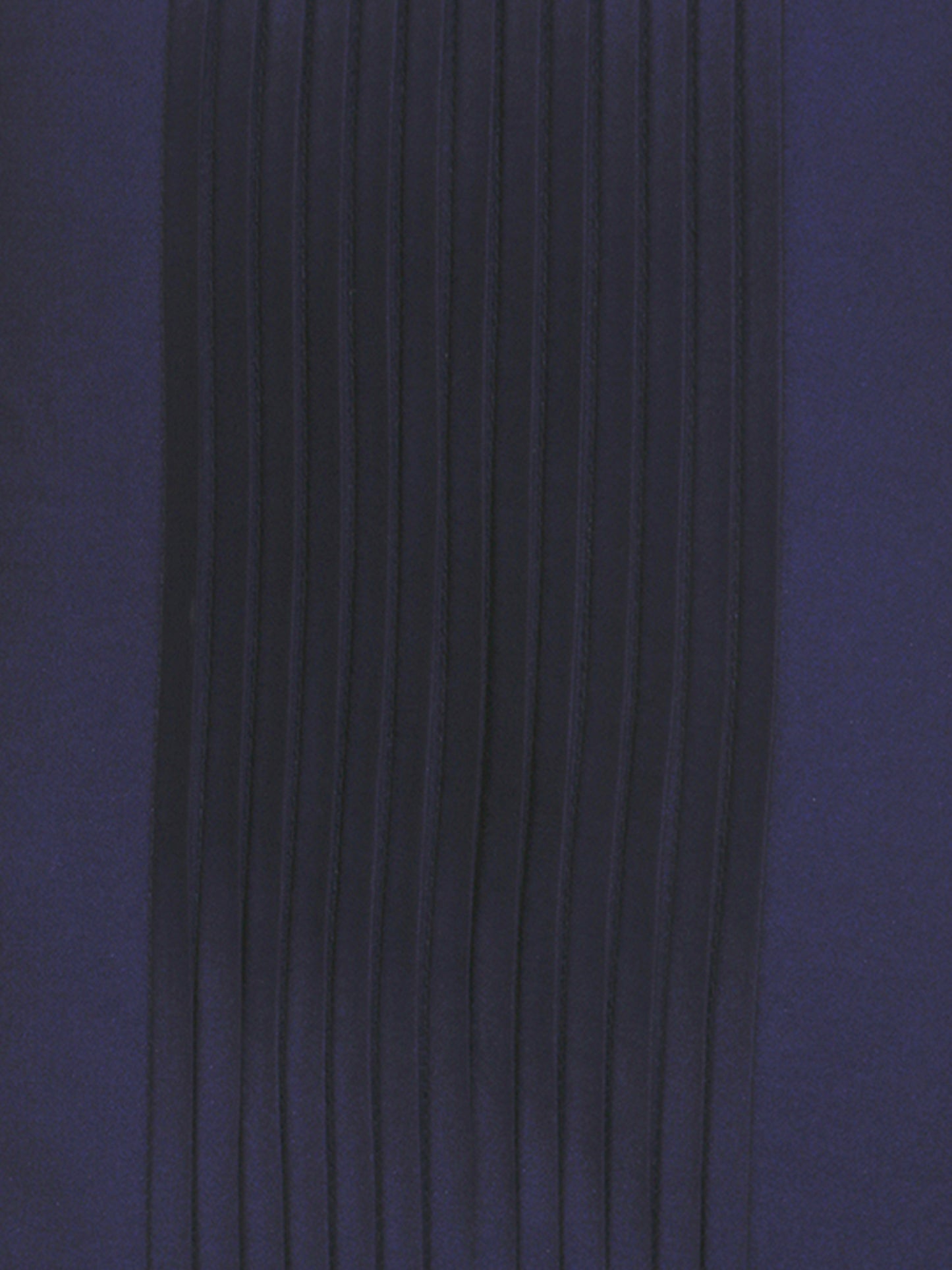 A close-up of dark navy blue pleated fabric with vertical folds on a matching solid navy background.