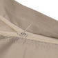 Close-up detail of a light beige fabric item with a cream zipper and a small metal pull tab, shown against a white background.