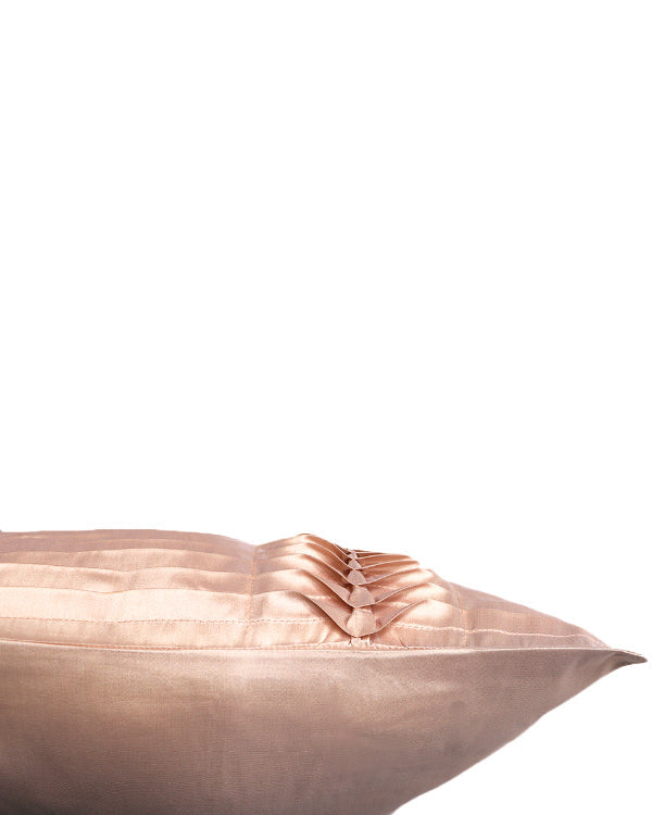 A close-up of a blush pink pillow with pleated fabric detailing, shown against a solid white background.