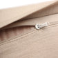 Close-up of a beige woven fabric item with a silver metal zipper pull, showing the texture and stitching details against a white background.
