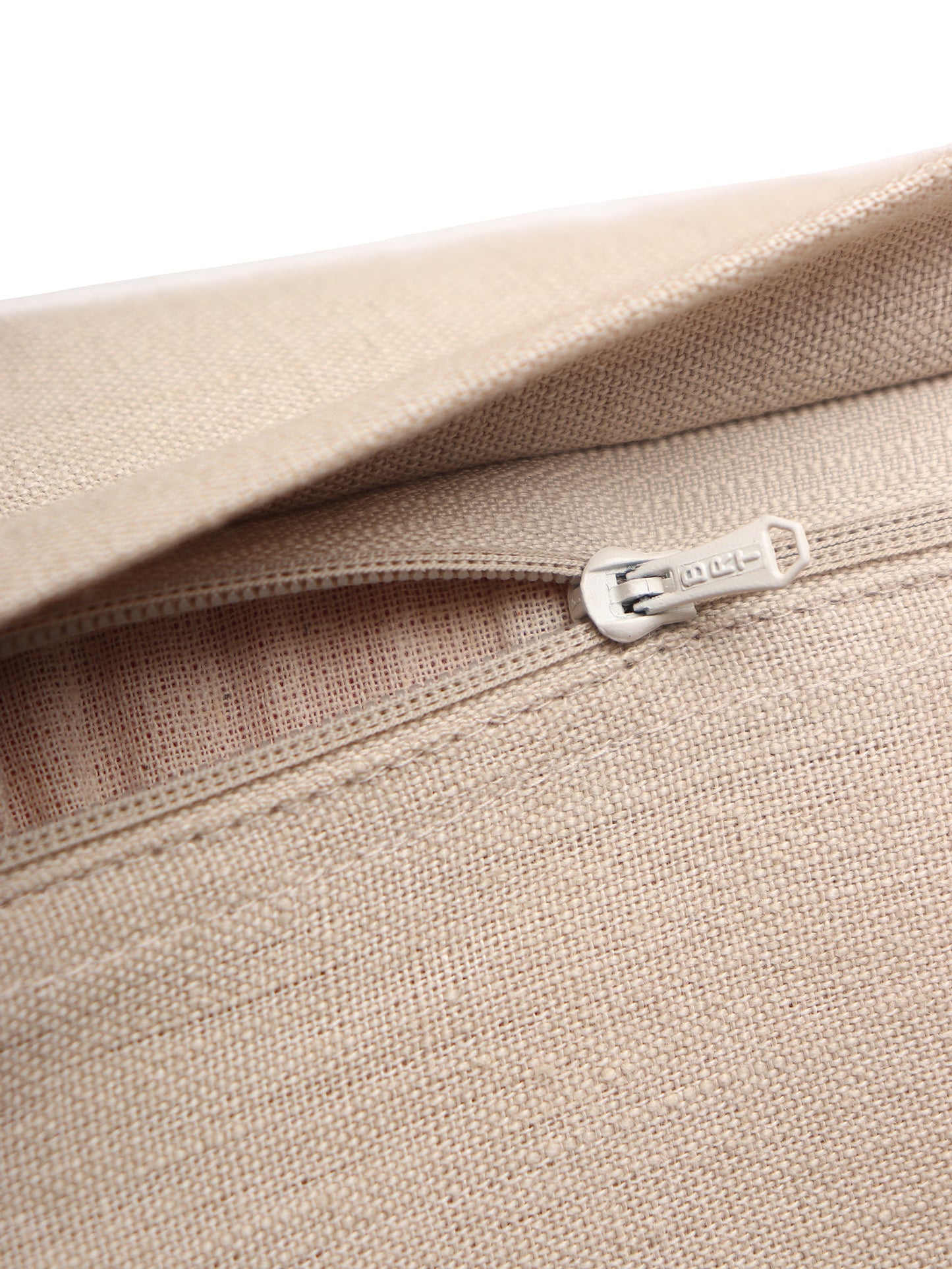Close-up of a beige woven fabric item with a silver metal zipper pull, showing the texture and stitching details against a white background.