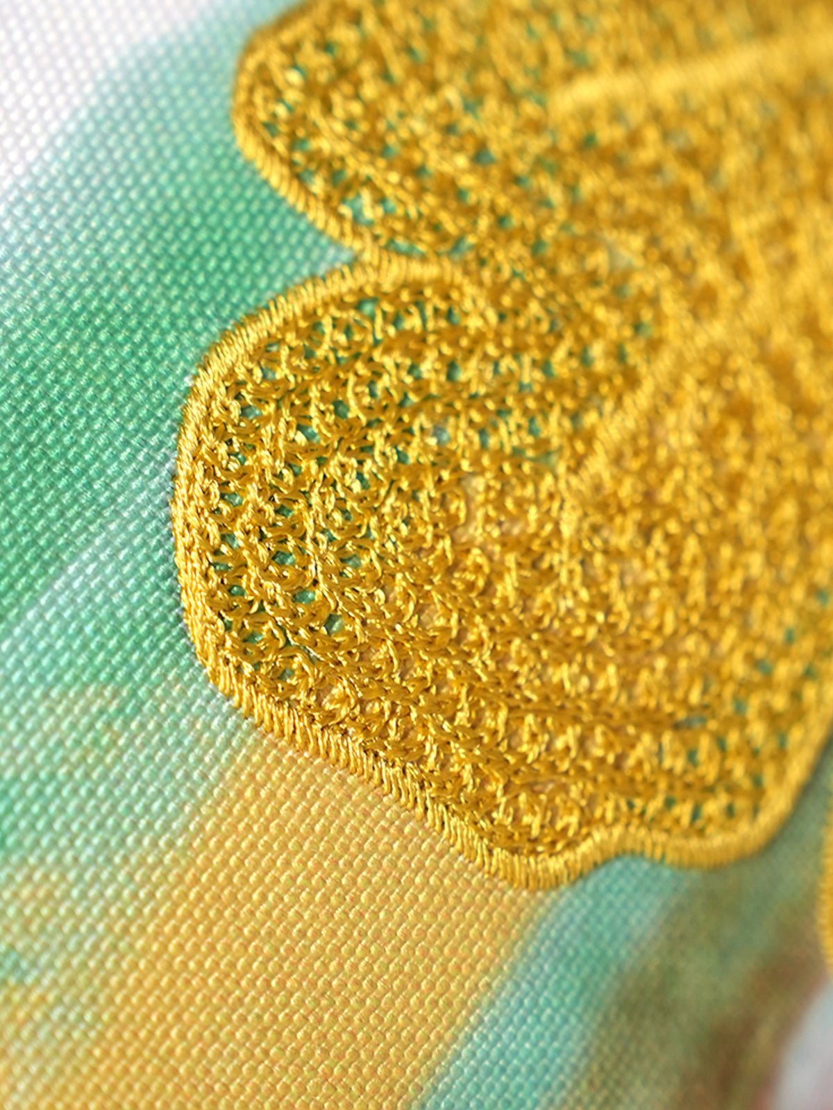 Close-up of a gold embroidered fabric on a green background