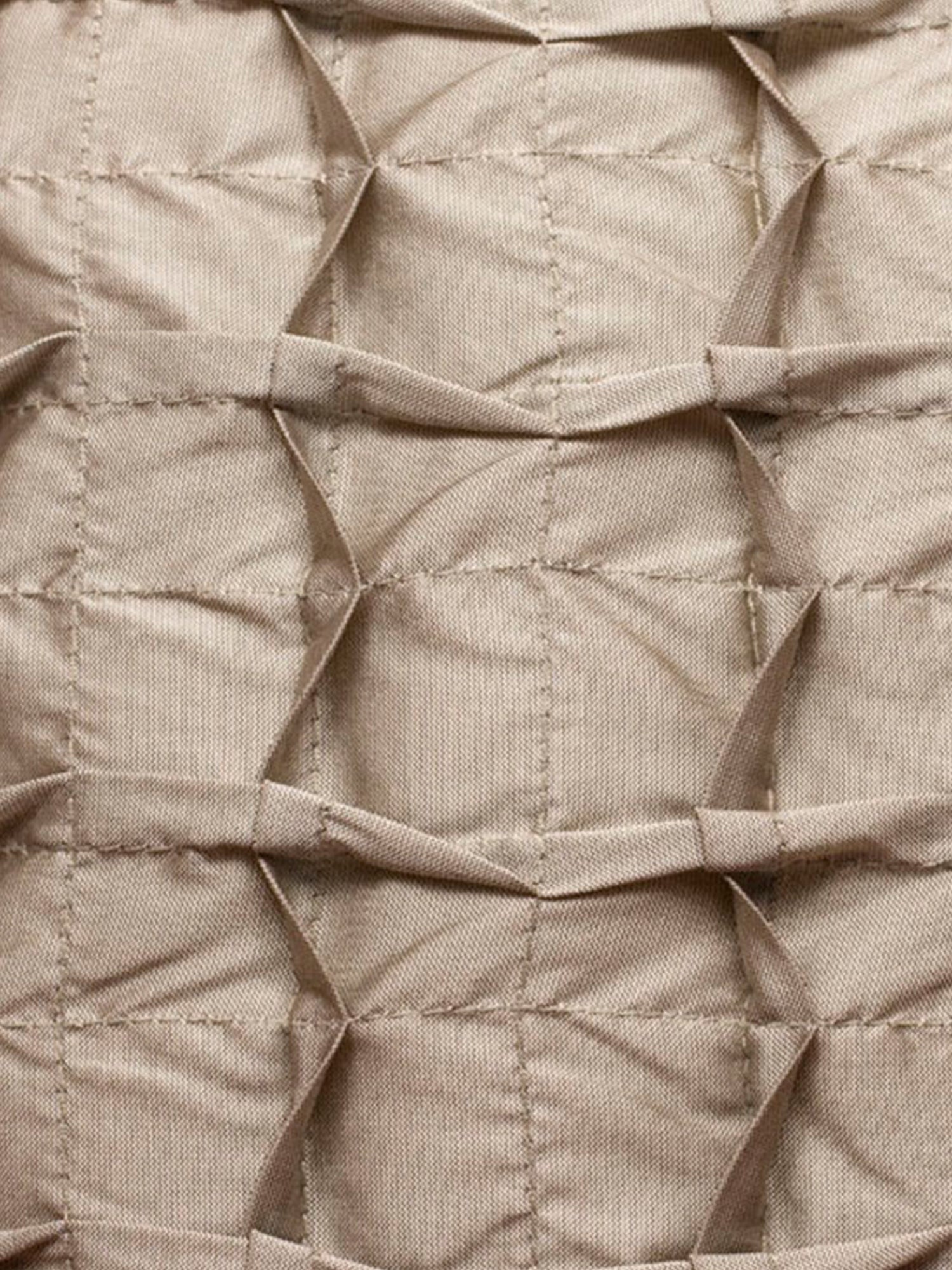 A close-up of a beige quilted fabric with a geometric pleated or diamond-stitched texture.